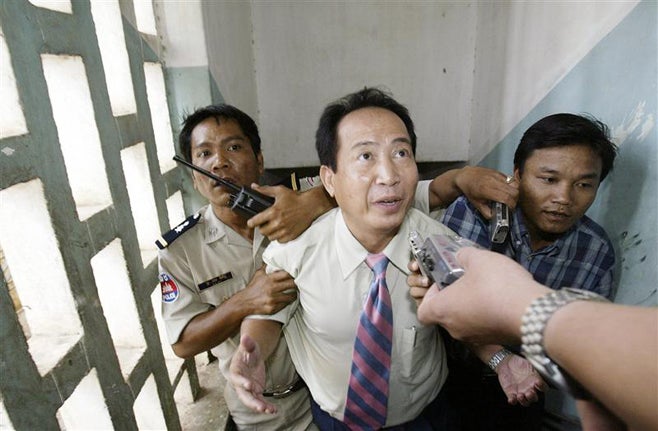 <p>Cambodian radio station director Mam Sonando is escorted by military police in Phnom Penh on October 11, 2005.</p>