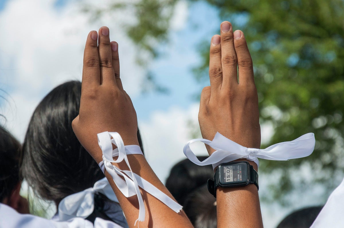 Students hold up a three finger salute during a protest.