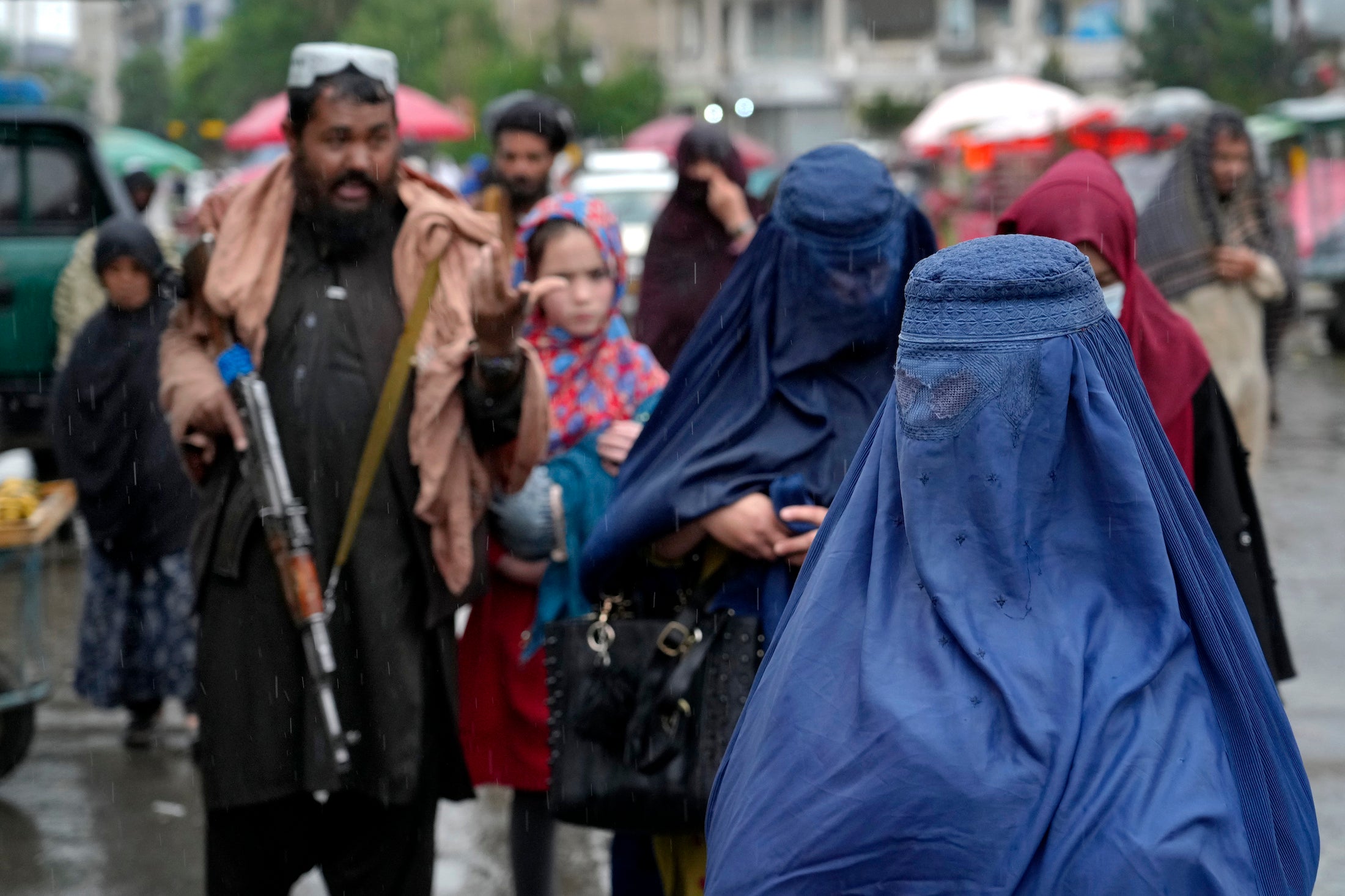 زنان افغان در حال قدم زدن در کنار نیروهای امنتیی طالبان، کابل، افغانستان، می 2002. 