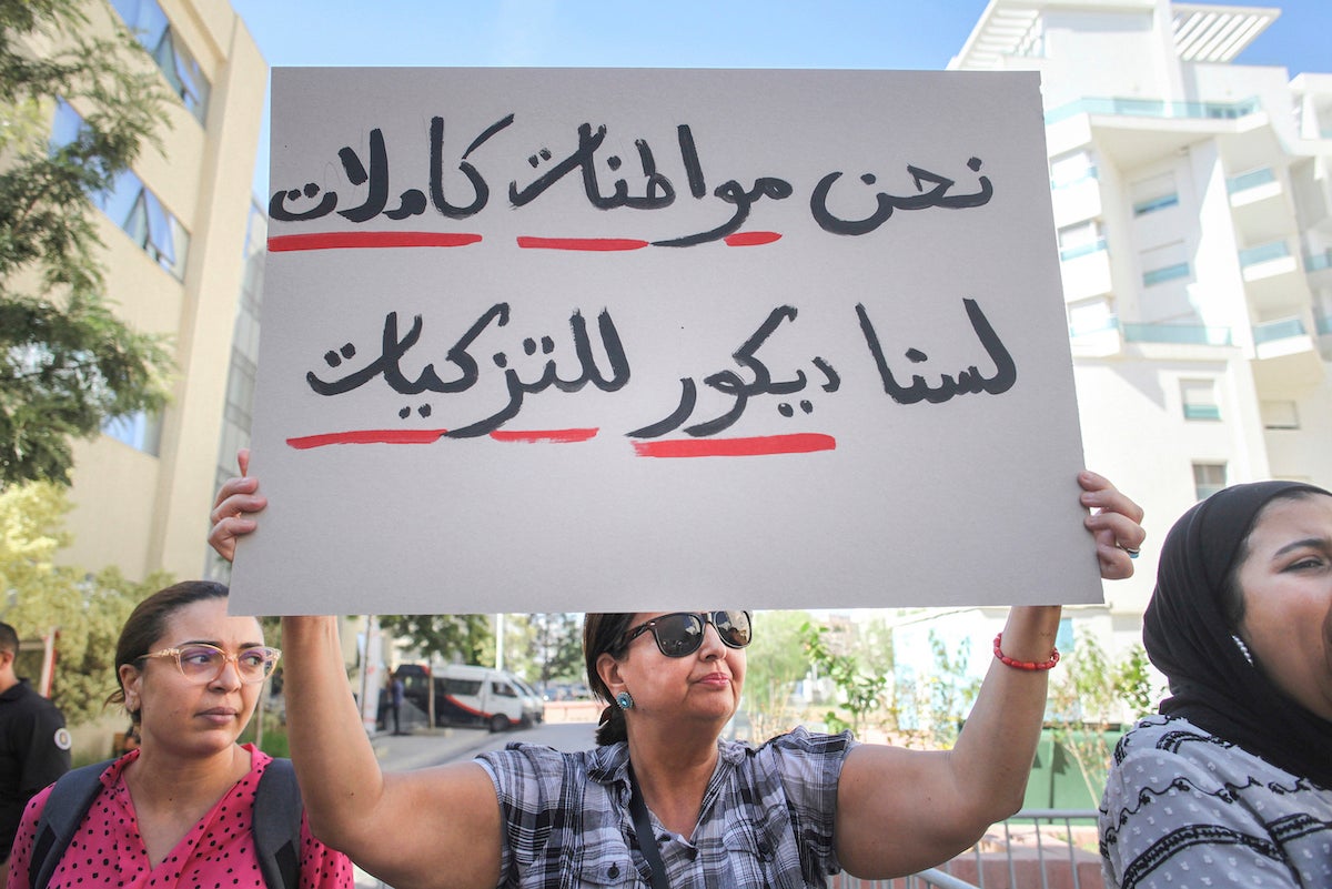 Cette femme tunisienne brandissait une pancarte comprenant l’inscription « Nous sommes des citoyennes à part entière » (en arabe), lors d'une manifestation à Tunis, le 7 octobre 2022. © 2022 Chedly Ben Ibrahim/AP Photo