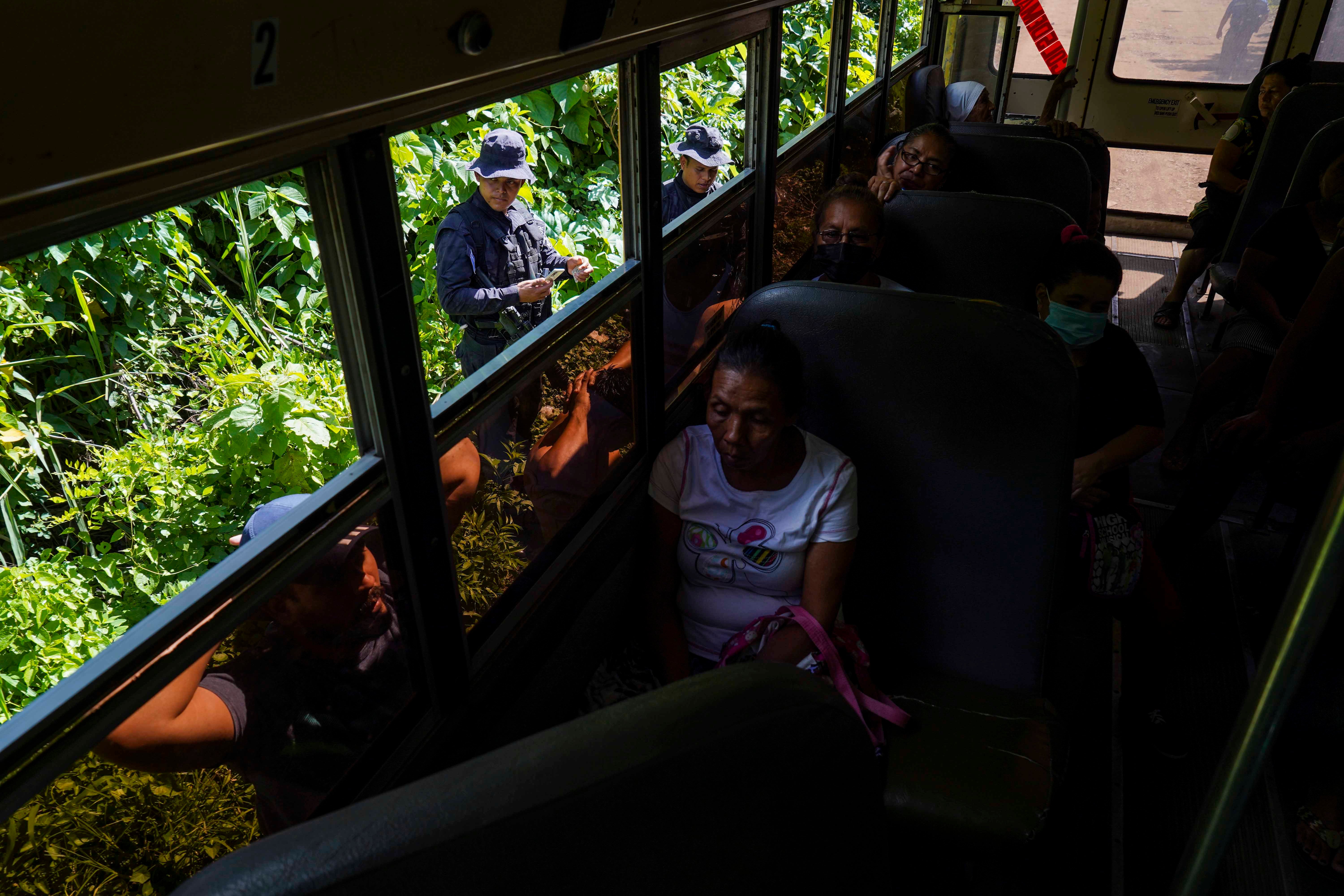 Des policiers salvadoriens contrôlaient les papiers d’identité de deux hommes qu’ils ont fait sortir d’un bus, lors d'une opération visant à identifier et arrêter des membres de gangs à Santa Ana, au Salvador, le 30 juin 2022.