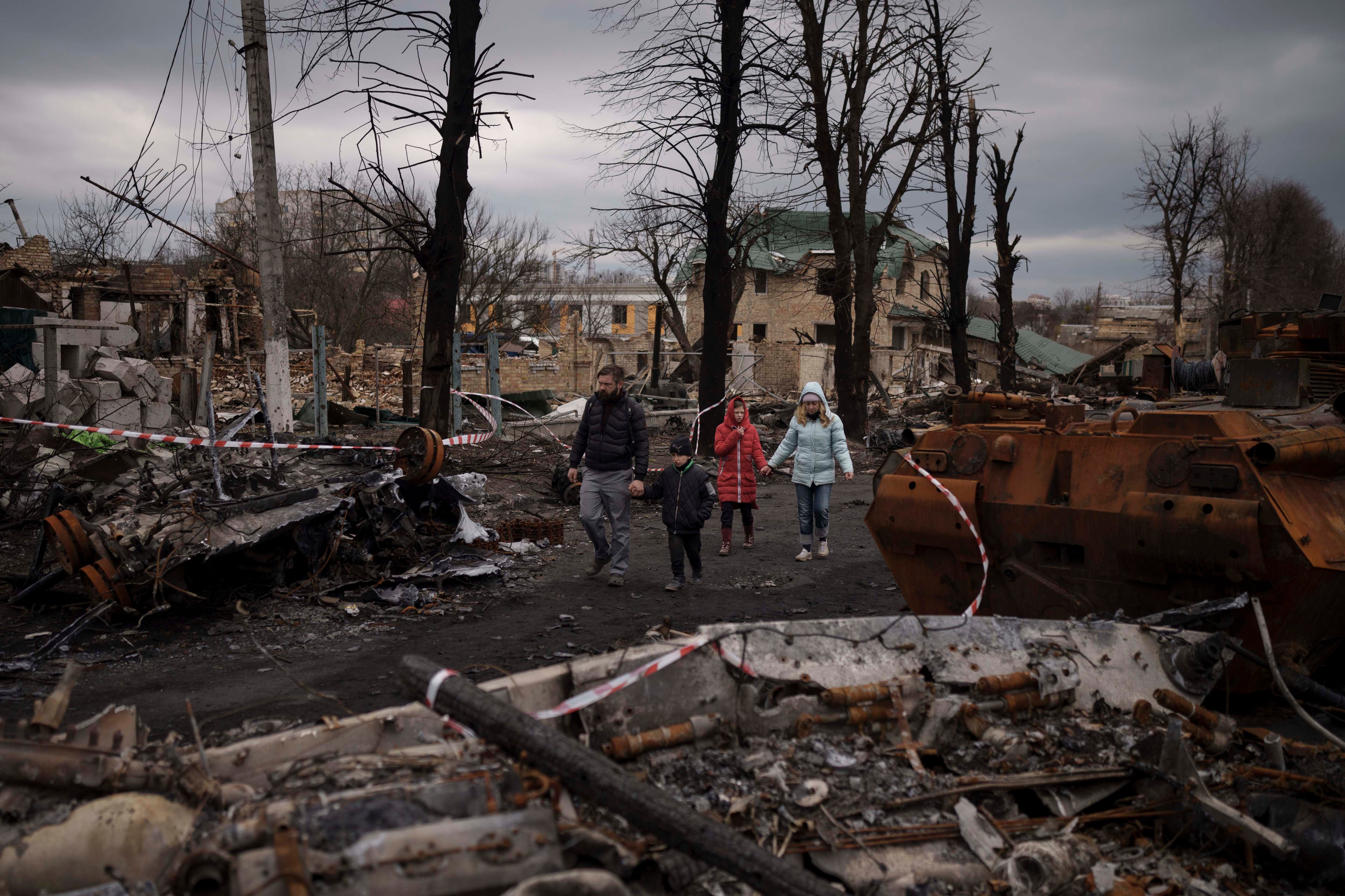 Eine Familie spaziert zwischen zerstörten Militärfahrzeugen in Butscha, in der Nähe der ukrainischen Hauptstadt Kiew am 6. April 2022.