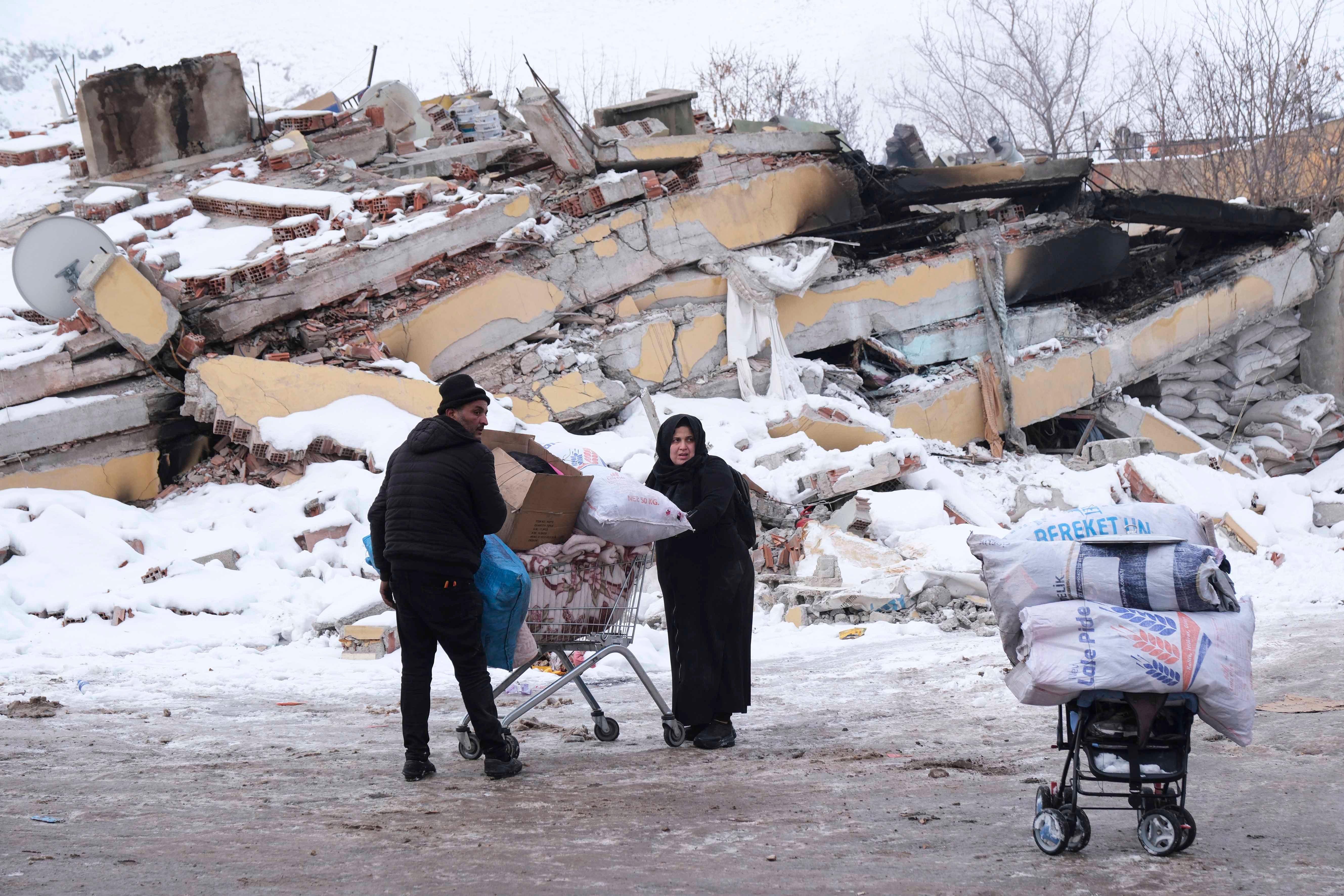 Elbistan, Kahramanmaraş'ta  alışveriş arabasıyla eşyalarını taşıyan Suriyeli bir mülteci çift, 8 Şubat 2023.