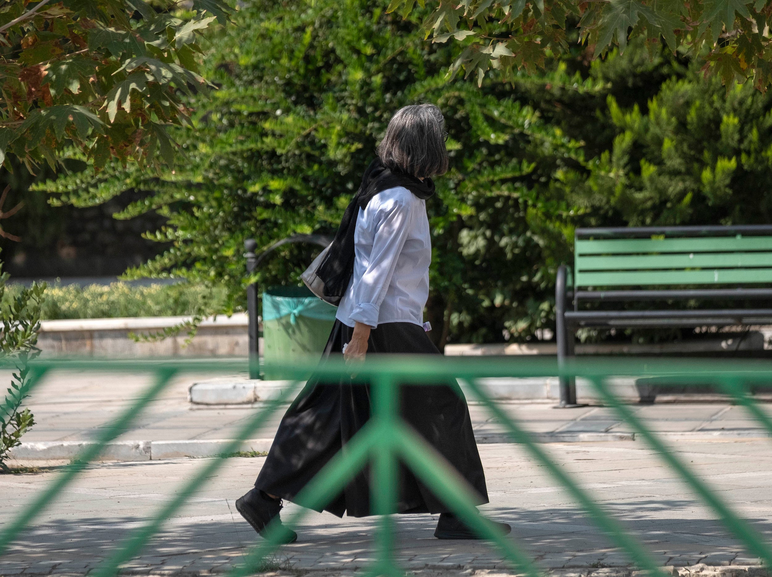An Iranian woman walks along a street-side in Tehran without wearing her headscarf.