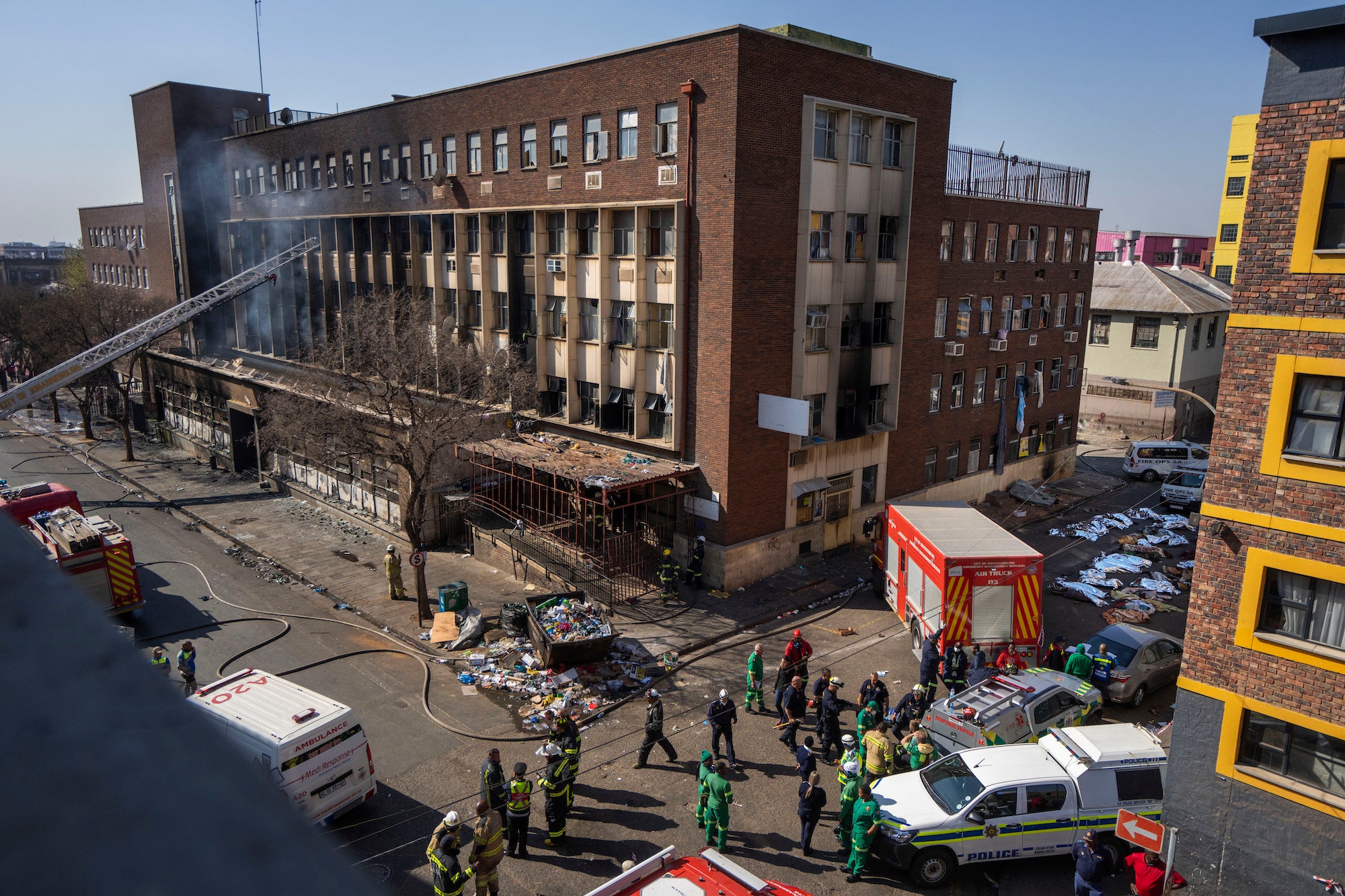 Medics stand by a burning apartment block in Johannesburg on August 31, 2023.