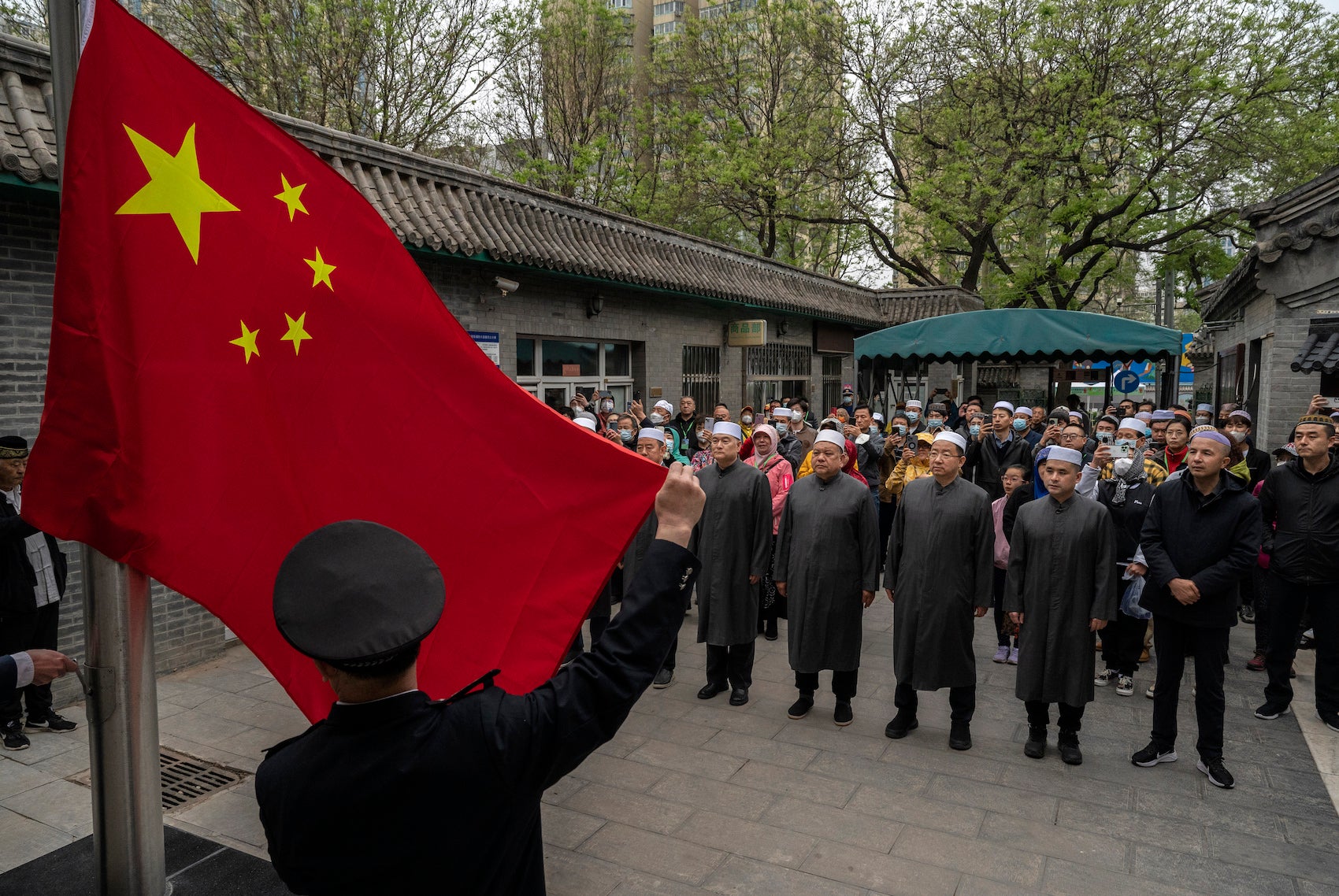 مصلون مسلمون صينيون يتجمعون بينما يُرفع العلم الوطني قبل صلاة عيد الفطر في مسجد نيوجي التاريخي في 22 أبريل/نيسان 2023 في بكين، الصين.