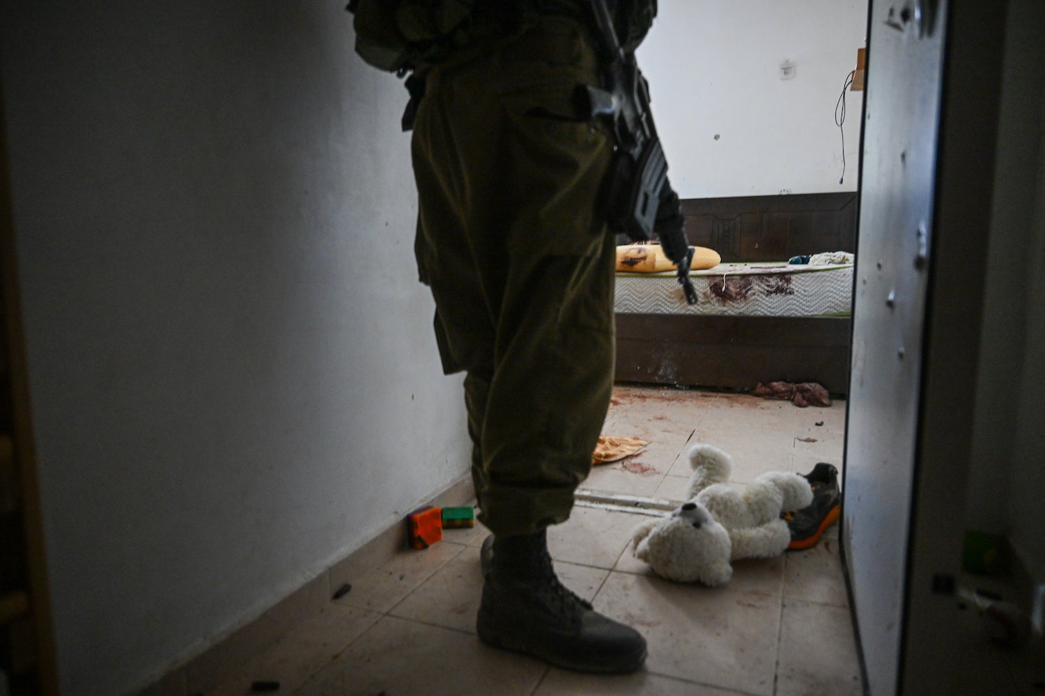 Un soldat israélien à l’entrée d’une pièce conçue comme abri anti-bombes dans une maison d'un kibboutz à Holit, dans le sud d’Israël, le 1er novembre 2023 ; un ours en peluche se trouvait encore par terre, suite à l’attaque menée par des combattants du Hamas le 7 octobre.