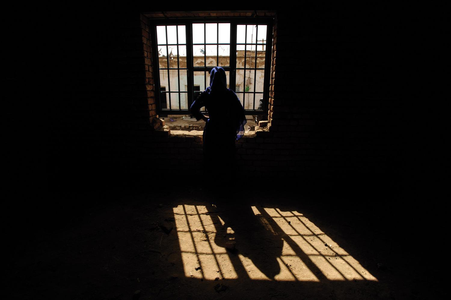 A woman prisoner looks out a window in Parwan prison north of Kabul, Afghanistan, in February 2011. The woman was convicted of moral crimes after a man from her neighborhood raped her. She later gave birth in prison.
