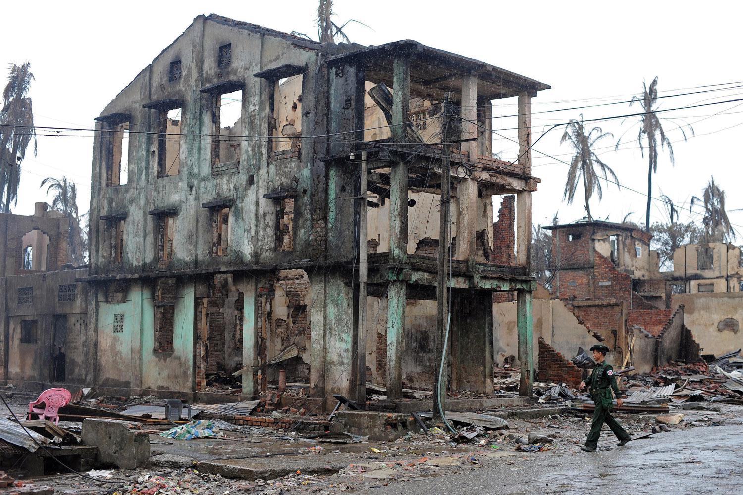 A Burmese soldier walks past a partially destroyed building in Sittwe, capital of Arakan State in western Burma, on June 14, 2012.
