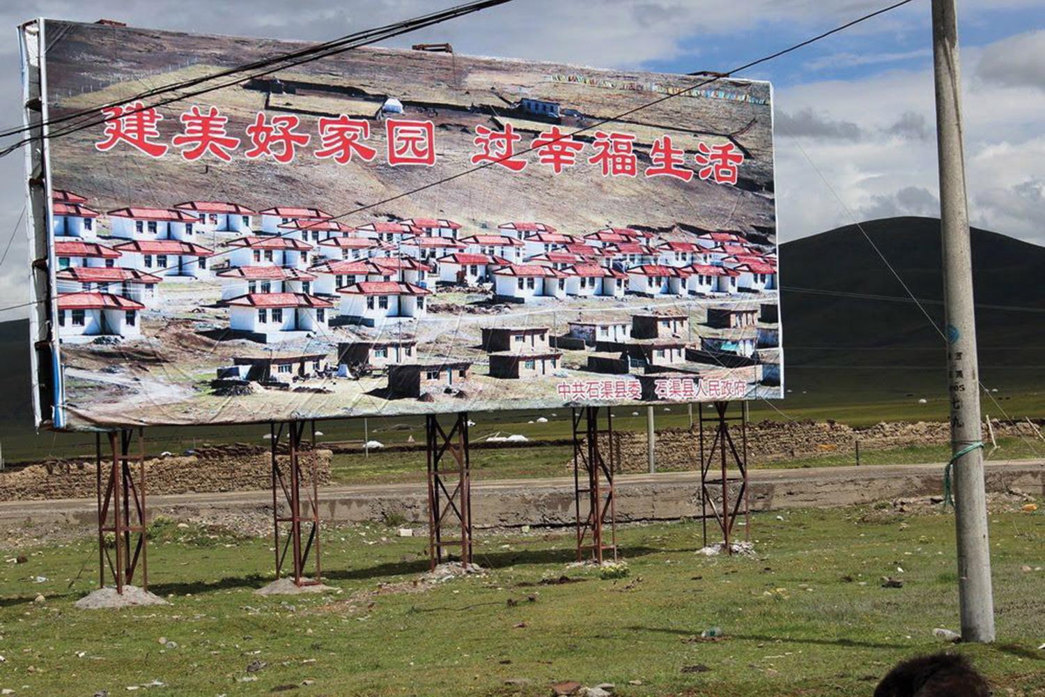 A propaganda billboard featuring a "New Socialist Village" in Sershul (Shiqu) County, Sichuan Province.  The billboard reads: "Build Beautiful Homeland, Live a Happy Life"