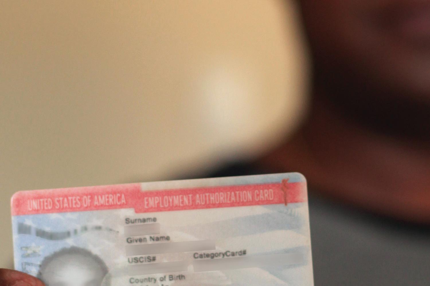 A man seeking asylum in the U.S. holds his work authorization card.