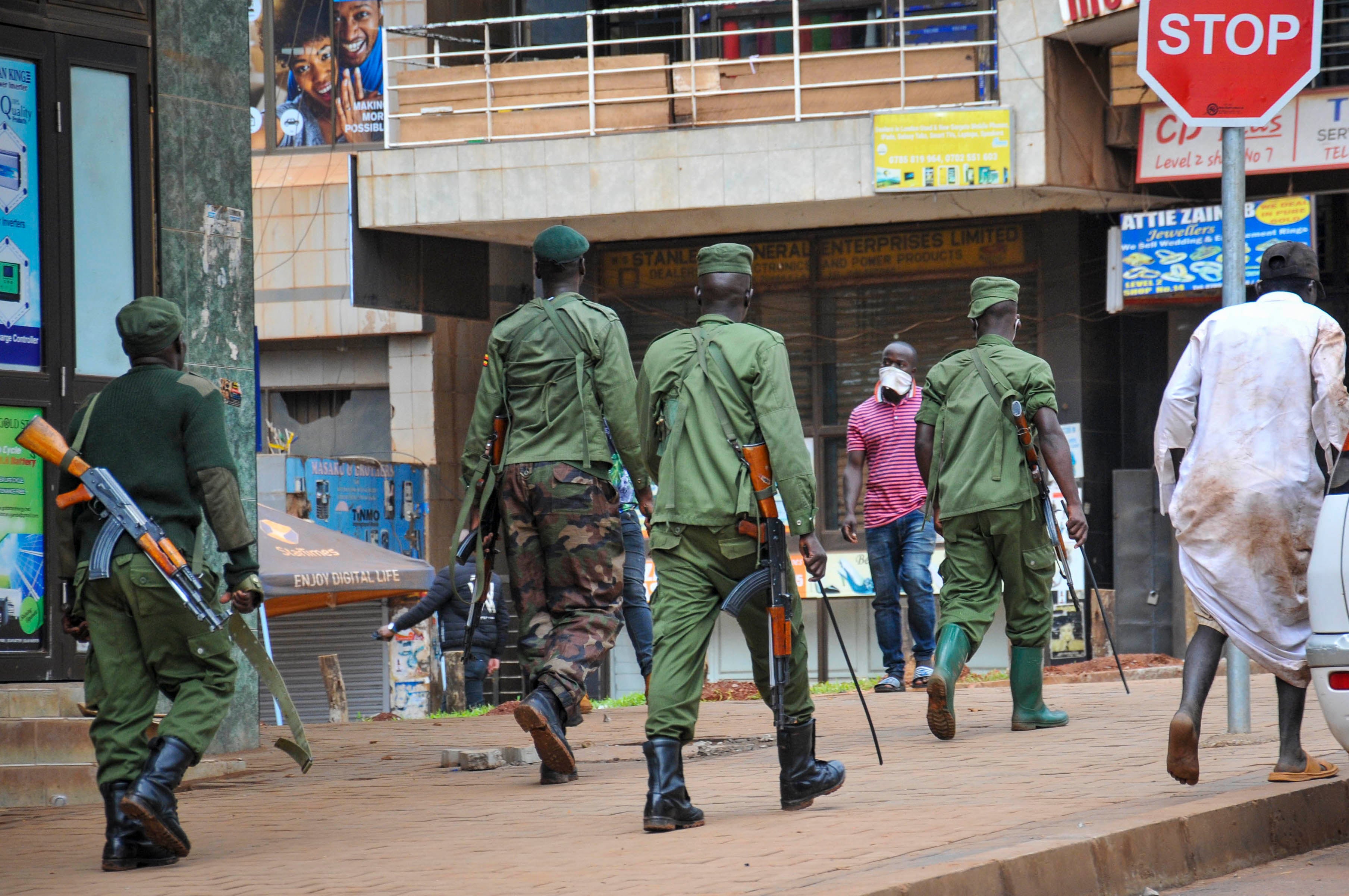 Des policiers et des membres des forces de sécurité patrouillent dans une rue de Kampala, en Ouganda, le 26 mars 2020, afin de veiller à la stricte application de mesures décrétées pour endiguer la propagation du coronavirus. 