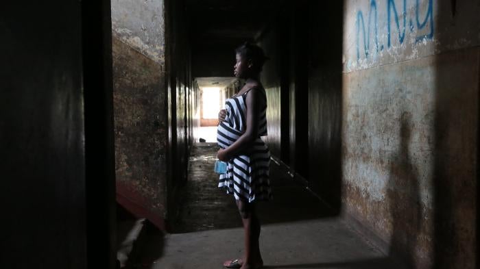 A 16-year-old girl who is pregnant stands in the hallway of her residence in Mbare township in Harare, Zimbabwe, November 2021.