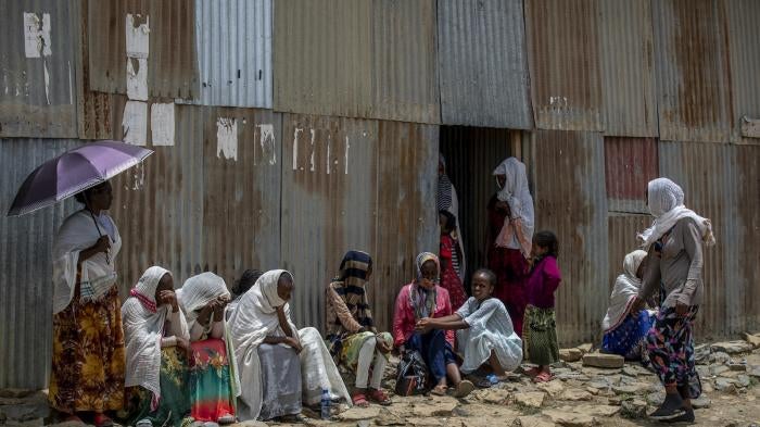 Displaced Tigrayans sit alongside metal shacks in Mekele, Ethiopia.