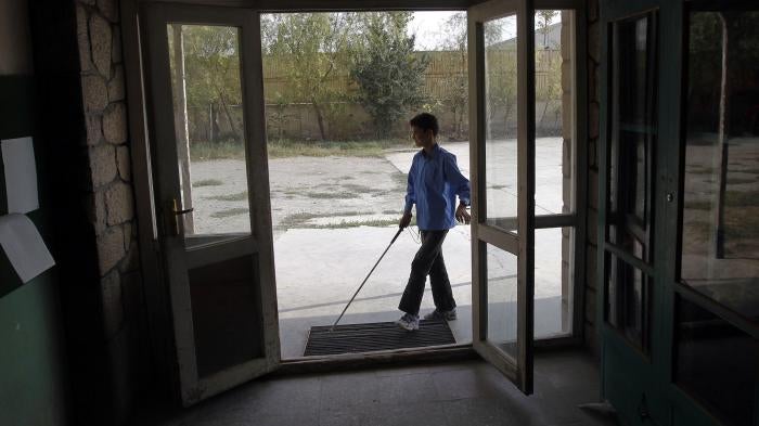 A student with a white cane arrives at a school in Kabul, Afghanistan.