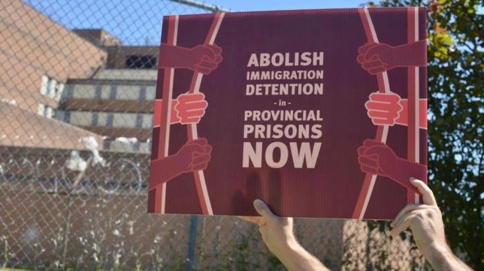 A protestor holds a sign outside a provincial jail in Toronto.