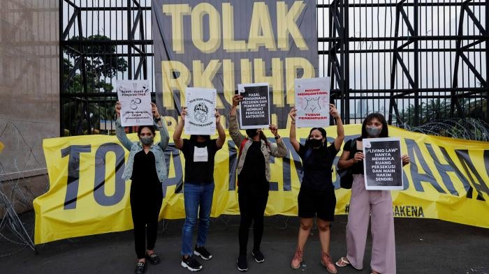 Protesters hold up signs outside parliament in Jakarta