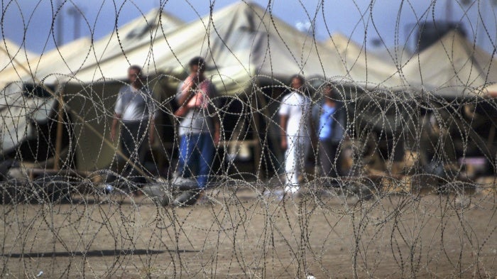 Prisoners stand next to the tents in which they are housed at the Abu Ghraib prison west of Baghdad, Iraq, July 15, 2004.