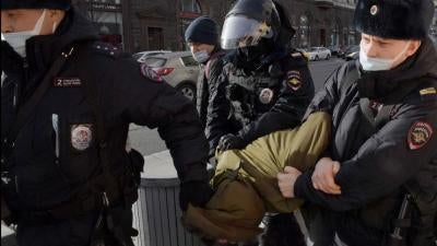 Three police officers arrest a protester and carry him away