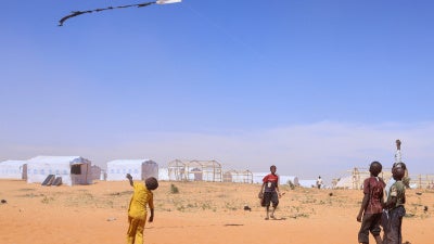 Sudanese refugee children from Darfur fly a handmade kite inside the Touloum refugee camp in Wadi Fira province, eastern Chad, November 30, 2025.