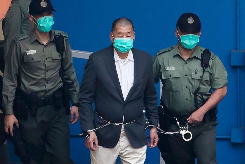 Jimmy Lai, fondateur du journal pro-démocratie Apple Daily, menotté et attaché par une chaîne à un agent des services pénitentiaires chinois, était amené afin de comparaître devant un tribunal a Hong Kong, le 12 décembre 2020.