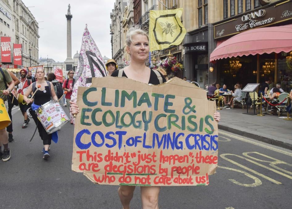 A protester holds a placard linking the climate crisis with the cost of living crisis