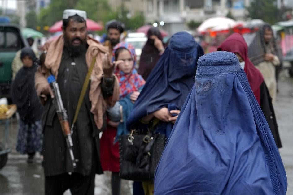 Beberapa perempuan Afghanistan berjalan melewati anggota pasukan keamanan Taliban di Kabul, Afghanistan, Mei 2022.
