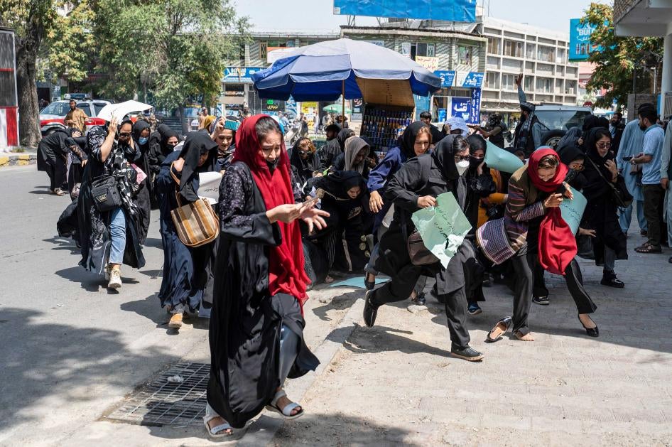 Des femmes afghanes qui participaient à une manifestation à Kaboul, le 13 août 2022, se sont mises à fuir quand des membres des forces de l’ordre talibanes (à l’arrière-plan) ont tiré en l'air pour disperser leur marche.