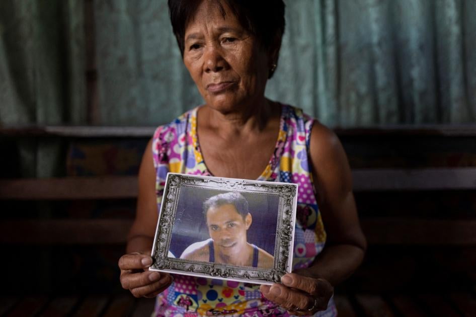 The mother of a "drug war" victim holds his portrait in her home in Caloocan City, Philippines.