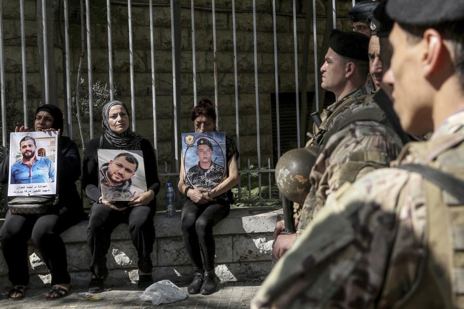 Families of the victims of the Beirut port blast hold pictures of their loved ones near Lebanese soldiers during a protest outside of the Beirut court, September 27, 2022. 