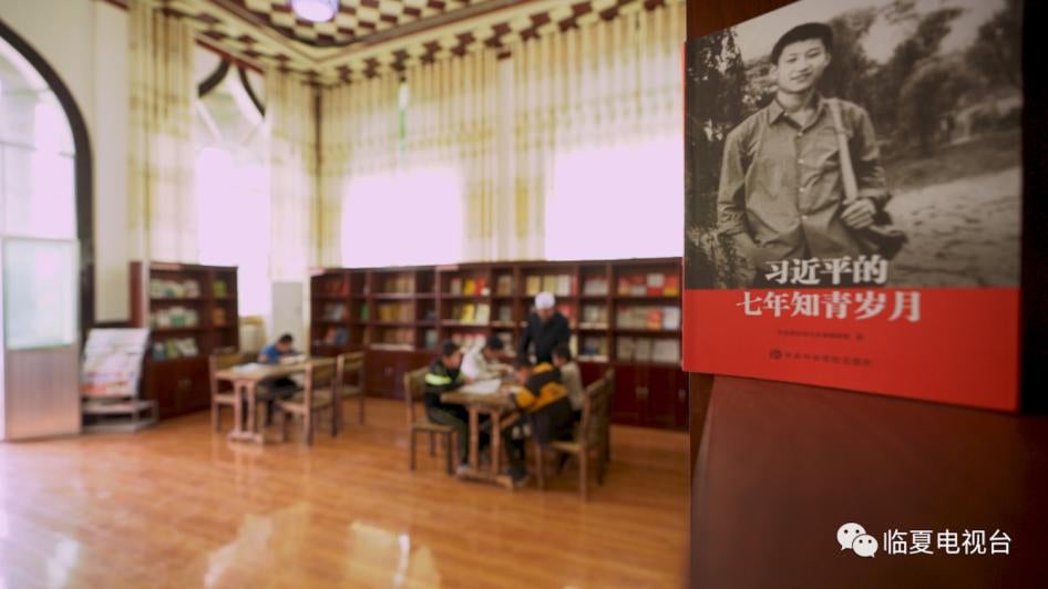 Cette image issue d’un message WeChat et diffusée le 14 mai 2020 par la chaîne de télévision d'État chinoise à Linxia montrait comment une des trois mosquées a été transformée en un espace de travail aux fins de « réduction de la pauvreté » et en un « centre culturel », où sont en vue un drapeau du Parti communiste chinois et une affiche montrant le président Xi Jinping dans sa jeunesse, dans le village de Huangniwan, situé dans la préfecture autonome Hui de Linxia, dans la province du Gansu. 