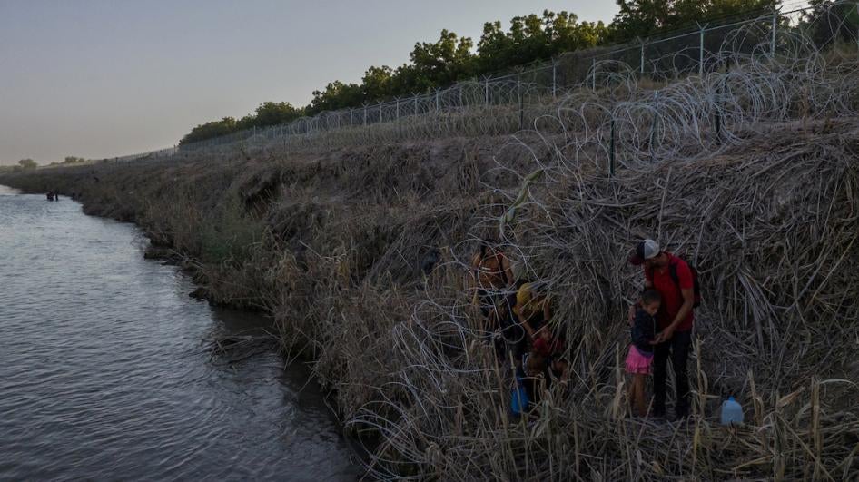 Migrant and asylum-seeker families navigate miles of concertina wire, ladened on the bank of the Rio Grande River, while searching for a clearance to enter the United States from Mexico in Eagle Pass, Texas, US, July 28, 2023. 