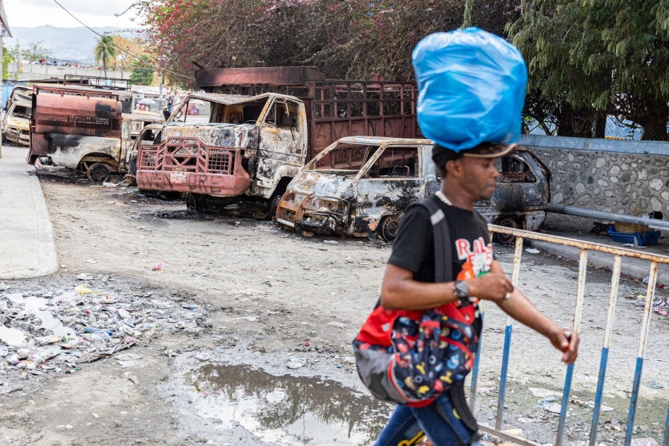 Un homme marchait près de plusieurs voitures incendiées par des groupes criminels dans le quartier Delmas 28 de Port-au-Prince, en Haïti, suite à des échanges de tirs entre des gangs et des policiers et soldats dans cette zone à proximité de l'aéroport, le 6 mars 2024. 