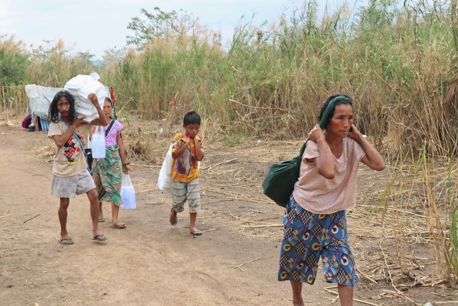 Displaced people from Myanmar carry donated lunch boxes to their tents along the Thai side of the Moei River in Mae Sot