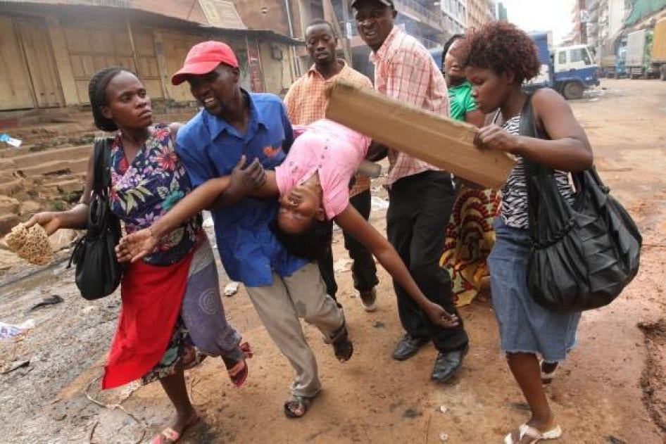 People carry away a woman, who fainted after being overcome by teargas during riots, in downtown Kampala on April 29, 2011, a day after people rallied in support of Uganda's opposition leader Kizze Besigye who had been arrested four times that month.