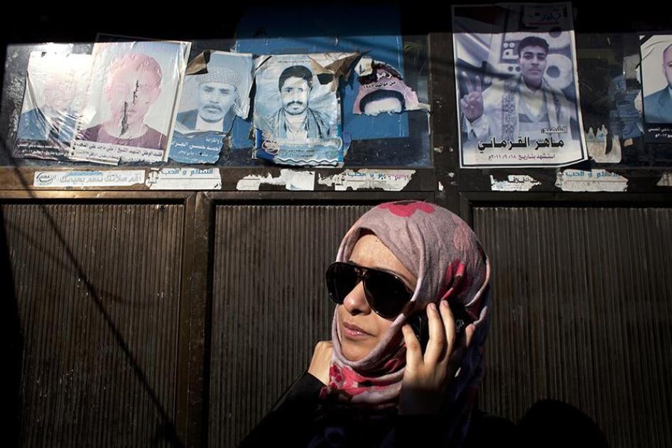 Sarah Jamal Ahmed, de pie junto a carteles con imágenes de manifestantes muertos colocados en la vía pública. Jamal Ahmed es una socióloga de 24 años y fue activista durante la revuelta de 2011 en Saná.