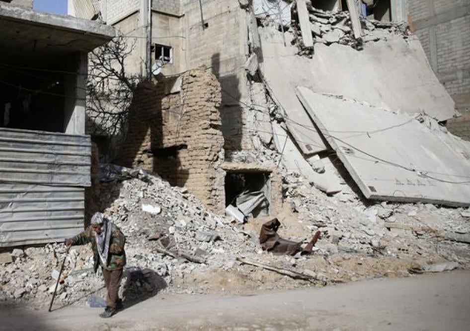 رجل مسن يمشي بالقرب من مبنى متضرر في بلدة دوما المحاصرة، الغوطة الشرقية، سوريا.