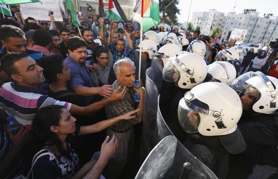 Une foule de manifestants face à des policiers anti-émeute dans la ville de Ramallah en Cisjordanie, le 23 juin 2014, lors d'un rassemblement tenu pour protester contre la collaboration en matière de sécurité entre l'Autorité palestinienne et Israël.
