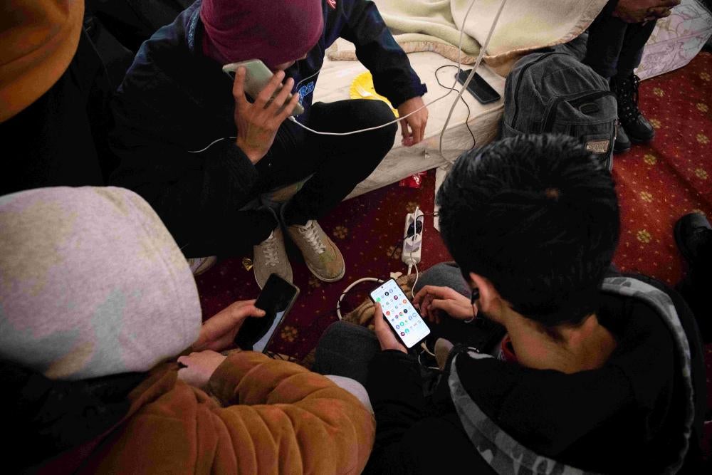Skupina Afganistancev polni svoje telefone pod okriljem pobude Karitasa in Jezuitske službe za begunce v Reki na Hrvaškem, april 2023. 