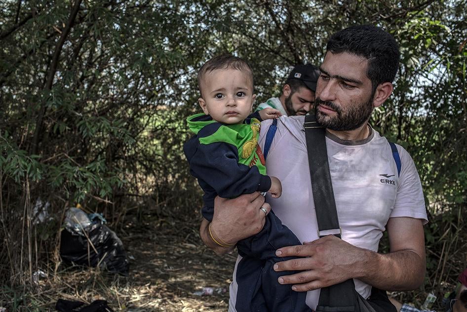 Mohammed, 31, a Syrian from Damascus carries his 9-month-old son at the Serbian-Hungarian border area near Horgos, Serbia on September 3, 2015. 