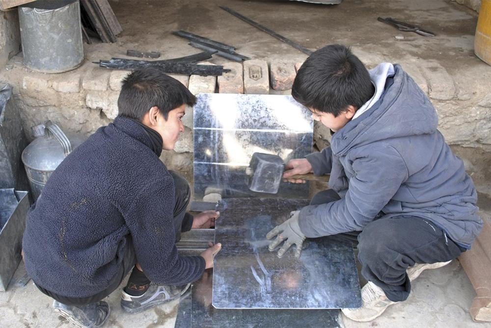 Mustafa, 14, and Hamid, 13, hammer sheet metal at a workshop in Kabul. Children continue to work in the sheet metal industry despite a government ban prohibiting them from working in hazardous industries. 