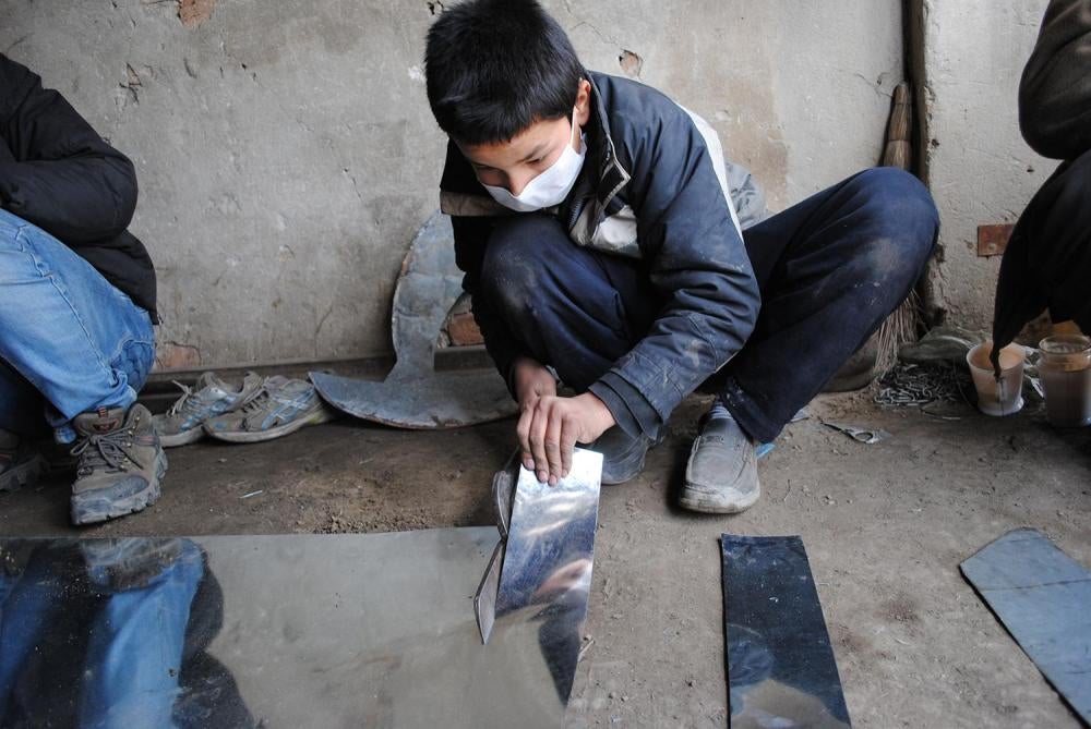 Mustafa, 14, cuts sheet metal at a workshop in Kabul. Sheet metal workers risk cuts and injuries from the metal’s sharp edges and from handling equipment designed for adult hands. 