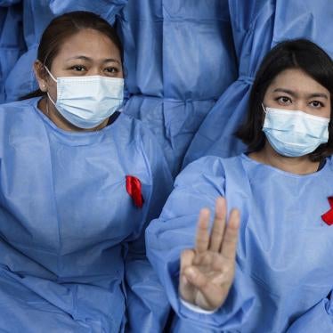 Medical staff in Myanmar wearing face masks and red ribbons raise the three finger salutes in protest against the military coup.