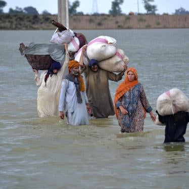 A displaced family wades through a flooded area in Jaffarabad