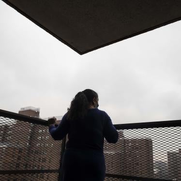 A woman looks out at a city from a patio