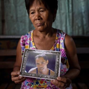 The mother of a "drug war" victim holds his portrait in her home in Caloocan City, Philippines.