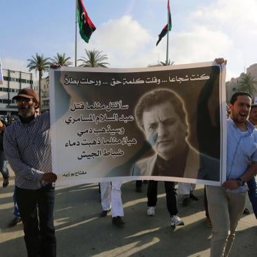 Protesters hold a banner bearing the portrait of Miftah Bouzeid, editor of the weekly newspaper BURNIQ, during a rally in Tripoli’s Martyrs’ Square to protest against his assassination. 