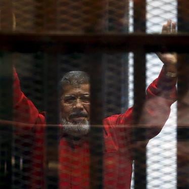 Deposed President Mohamed Morsy, wearing the red uniform of a prisoner sentenced to death, greets his lawyers and people from behind bars during his June 2015 court appearance with Muslim Brotherhood members on the outskirts of Cairo. © 2016 Reuters