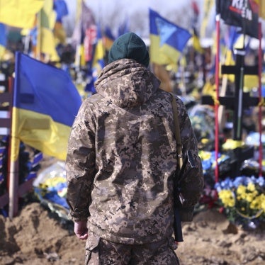 A Ukrainian soldier stands in front of the graves of Ukrainian soldiers killed in the war at a cemetery in Kharkiv.