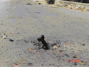 An unexploded mortar shell burrowed into a road in South Lebanon.  The threat from unexploded ground and naval launched artillery will remain a persistent hazard to both humanitarian aid workers and the local population until it is located and destroyed.  © 2006 UN Mine Action Coordination Center for South Lebanon. August 15, 2006.<br />
